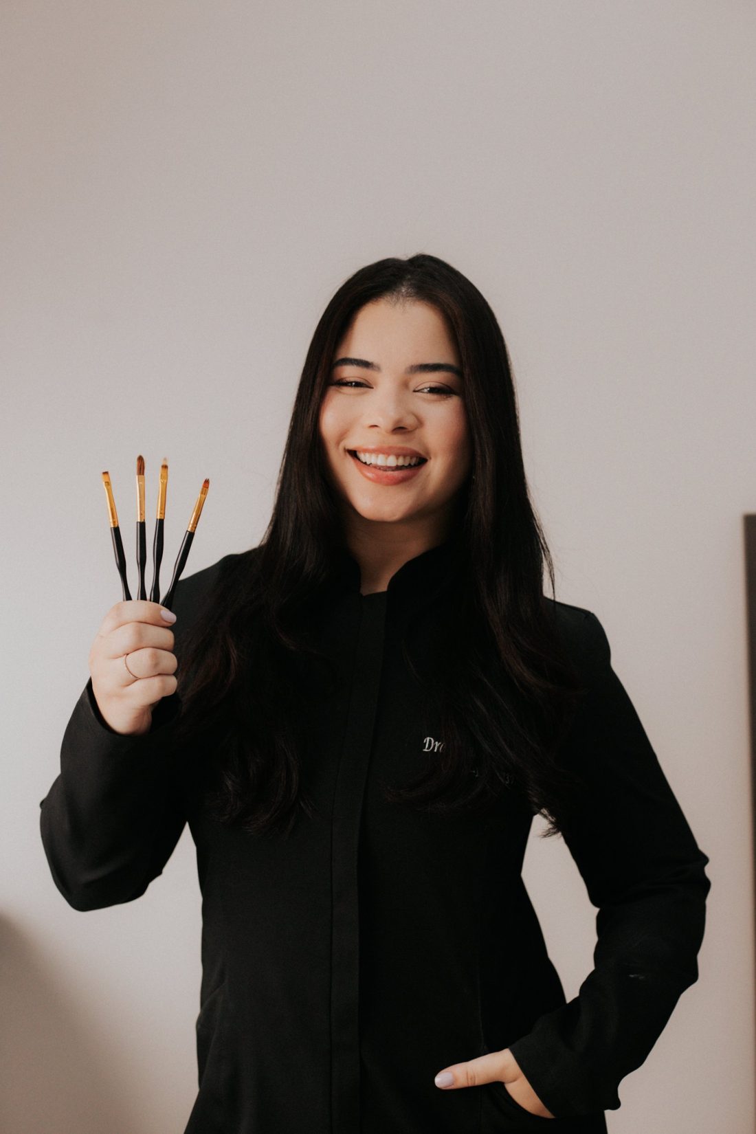 Dra. Vanessa Andrade sorrindo, segurando pincéis odontológicos